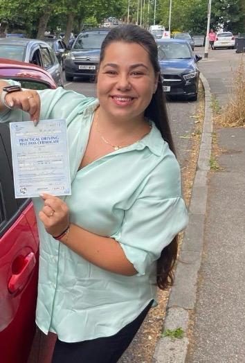 A pupil holding their practical driving test pass certificate after passing with MK Driving School in East London, July 2024